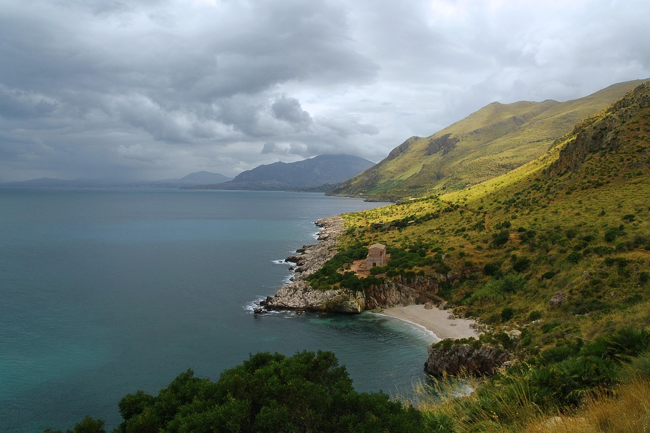 Spiaggia di sabbia dorata con acque cristalline e scogliere nella Sicilia sud-orientale.