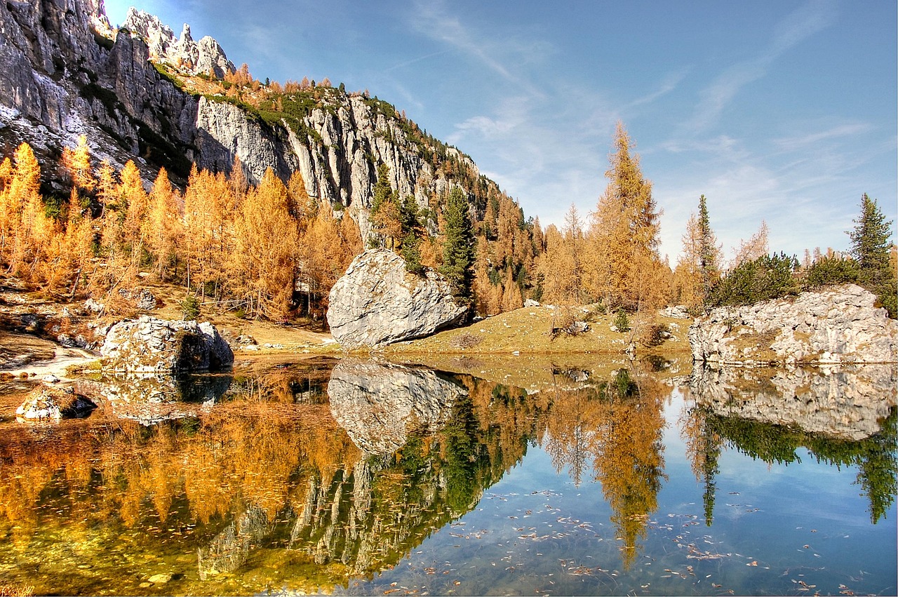 Panorama autunnale del lago di Braies con foglie colorate e montagne sullo sfondo.