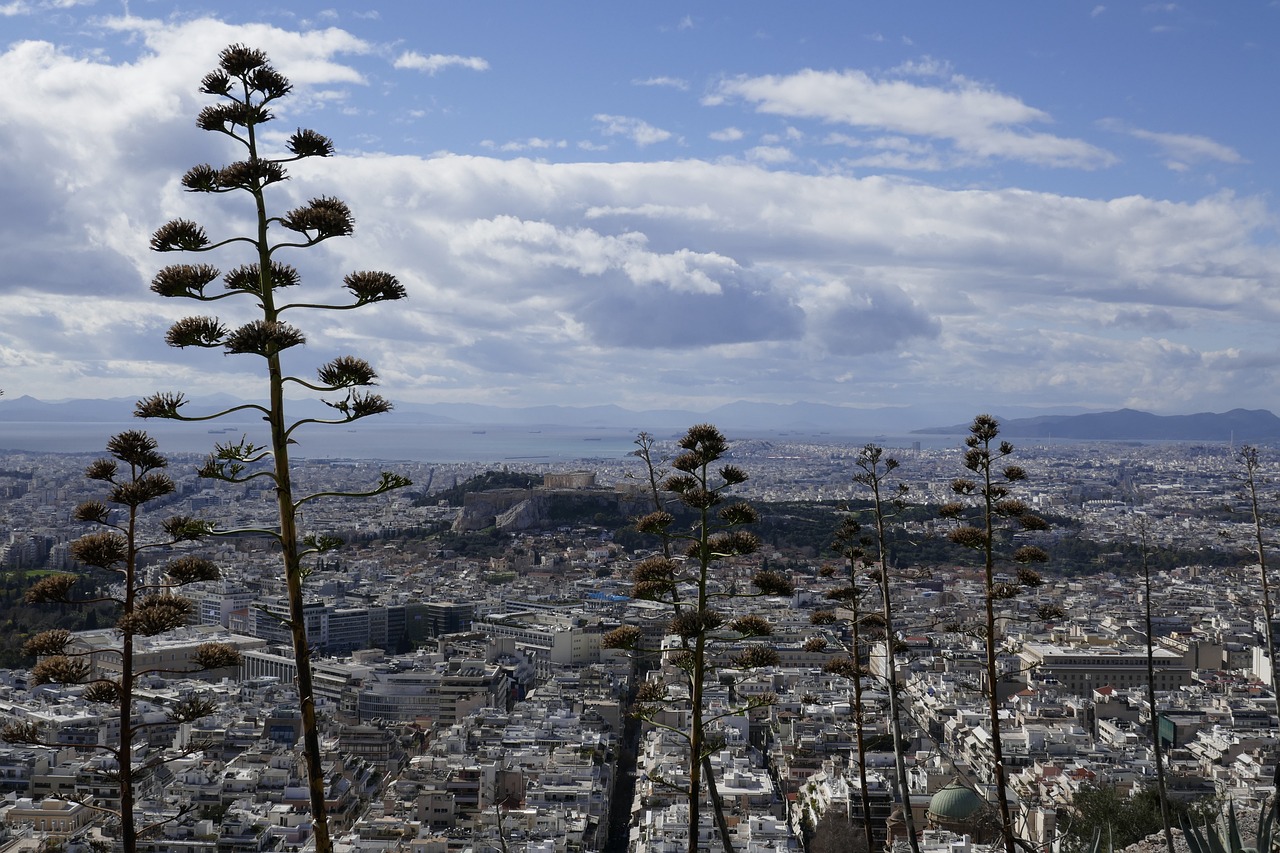 Panorama di Atene in estate, con cieli sereni e turisti sotto il sole cocente.