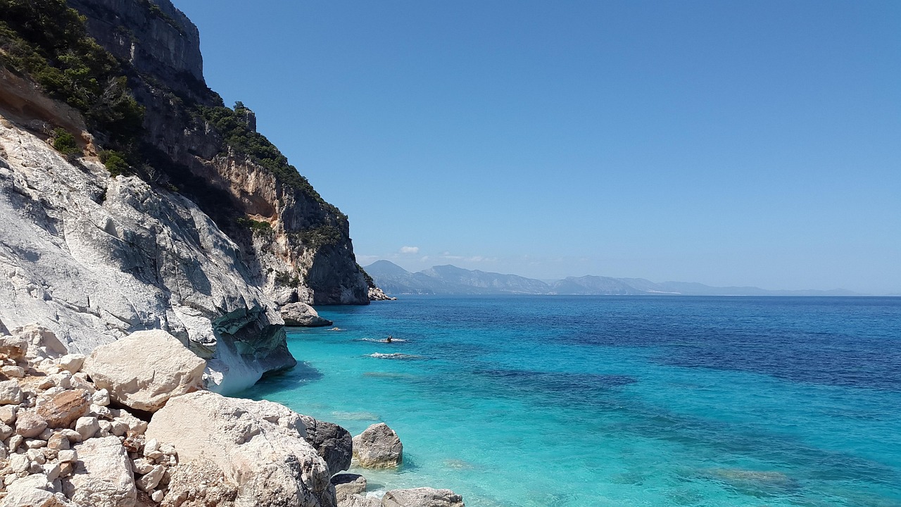 Vista panoramica di una piscina naturale in Sardegna, circondata da rocce e vegetazione lussureggiante.