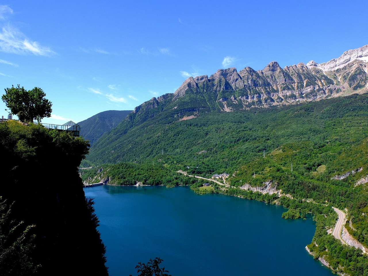 Vista panoramica del lago incantevole, circondato da montagne e vegetazione lussureggiante.