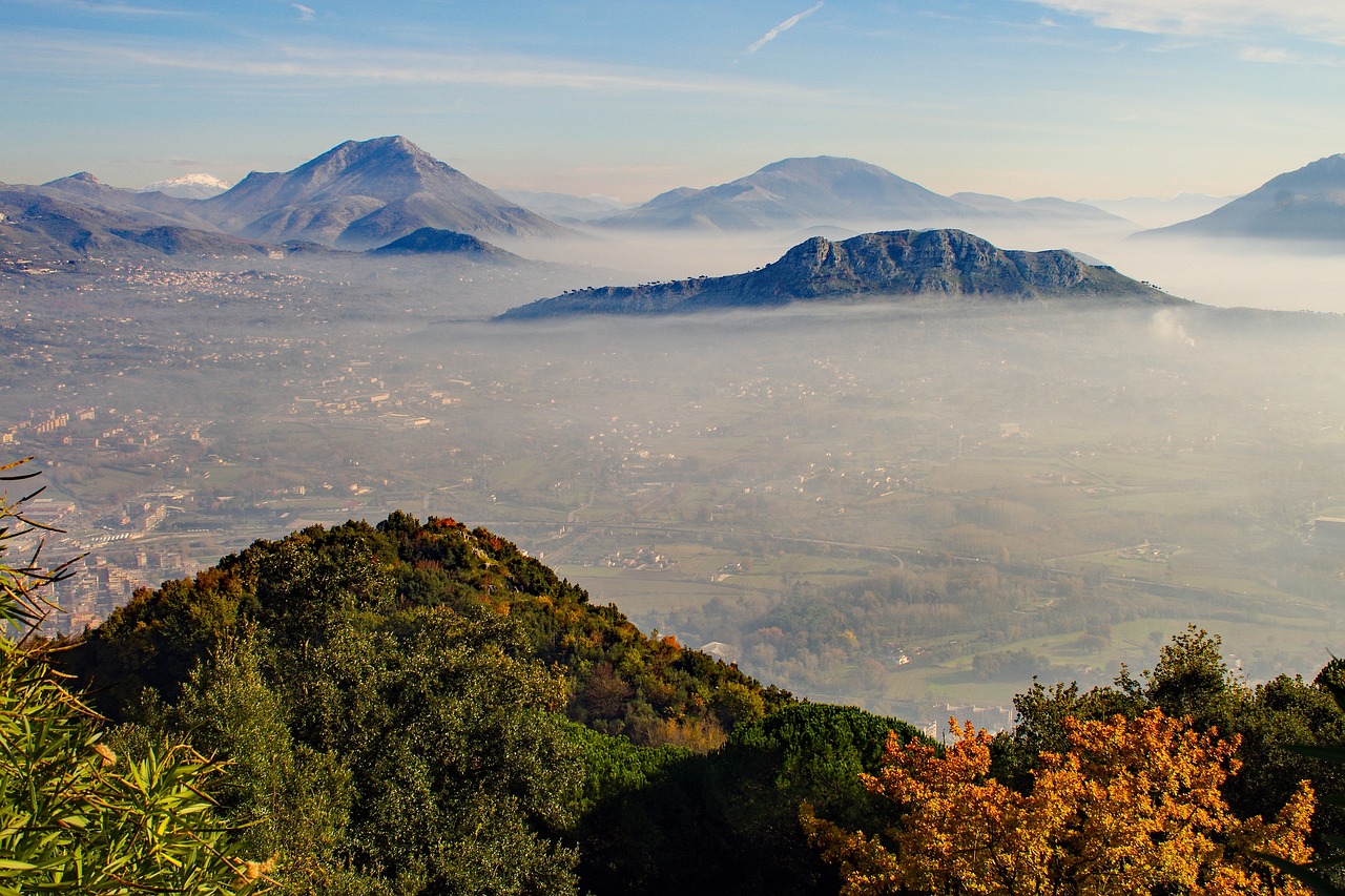Veduta del borgo di Erice avvolto nella nebbia, con castelli e dolci genovesi in primo piano.