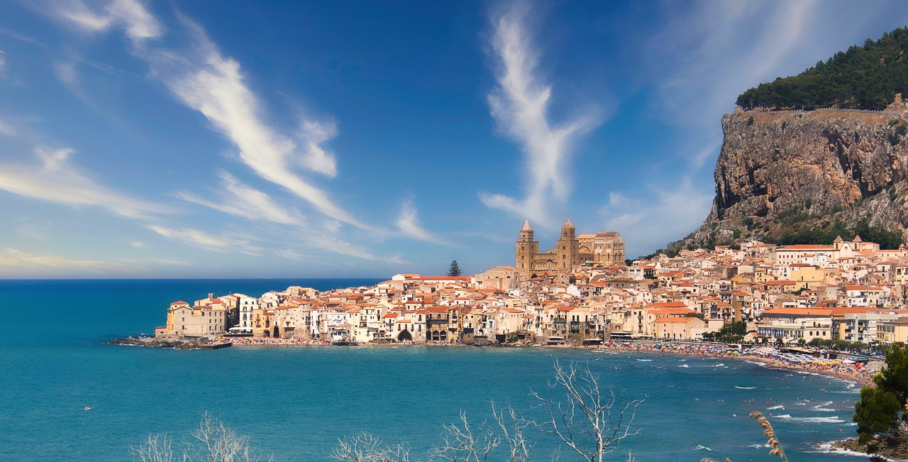 Cefalù: vista panoramica del borgo con mare cristallino e cattedrale normanna sullo sfondo.