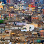 Borgo italiano vivace e colorato, con case dai toni brillanti che ricordano un dipinto.