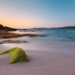 Spiaggia delle Baleari con sabbia bianca e acque cristalline, ideale per una vacanza estiva in Spagna.