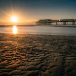 Vista panoramica della località di mare con spiagge affollate e turisti felici.