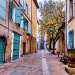 Panorama di una pittoresca cittadina francese con stradine acciottolate e case colorate.