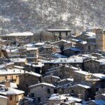 Borgo invernale deserto, con strade ghiacciate e atmosfera desolata, evidenziando i disagi della stagione fredda.