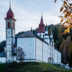 Castello emiliano fiabesco con torri e merlature, circondato da alberi e un cielo sereno.