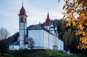 Castello emiliano fiabesco con torri e merlature, circondato da alberi e un cielo sereno.