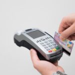 Commerciante che utilizza un POS per effettuare un pagamento, con focus sulle nuove regole.